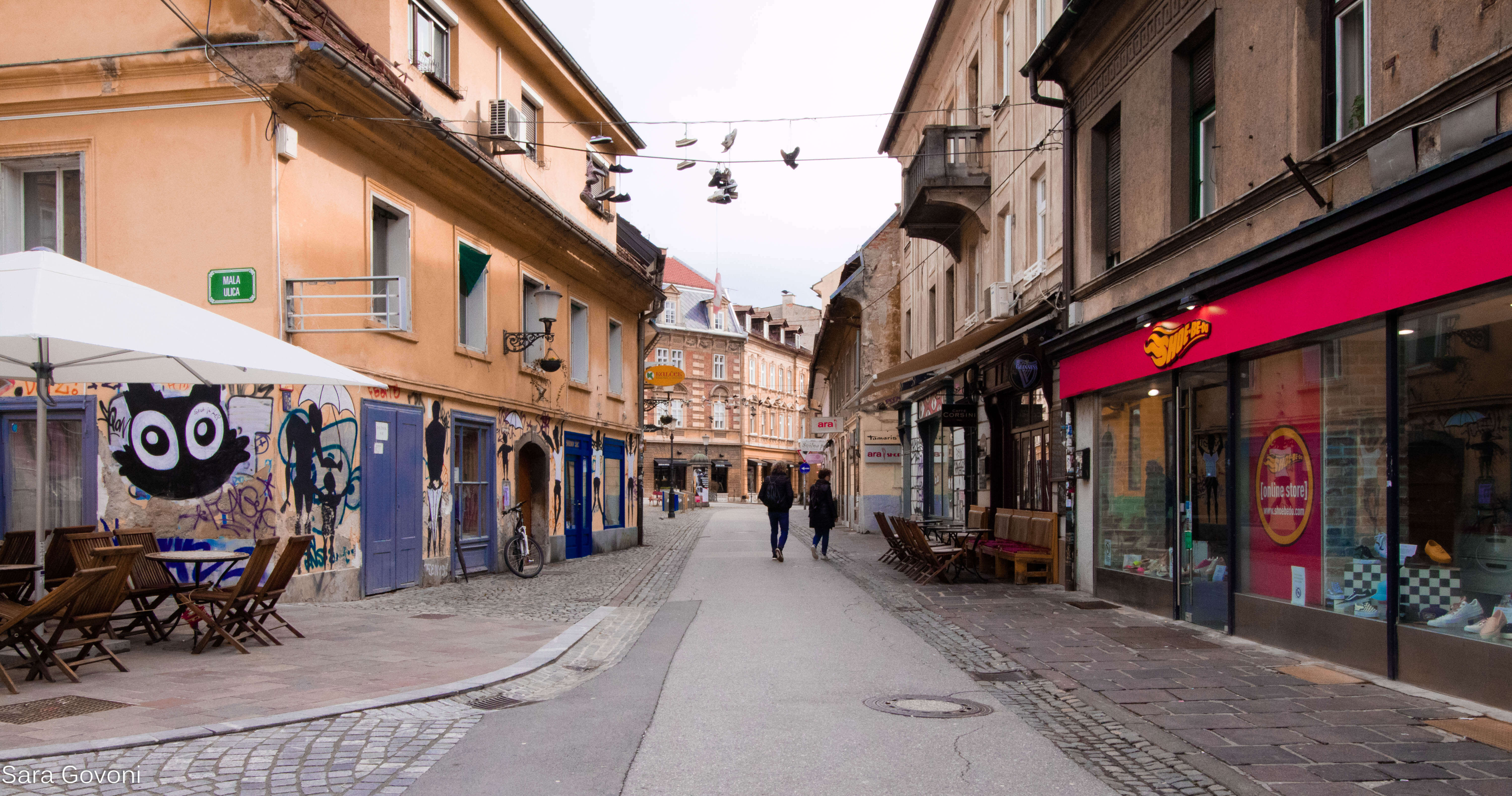 Cosa vedere a Lubiana in un giorno: via con scarpe appese ai fili, negozi e vetrine colorate